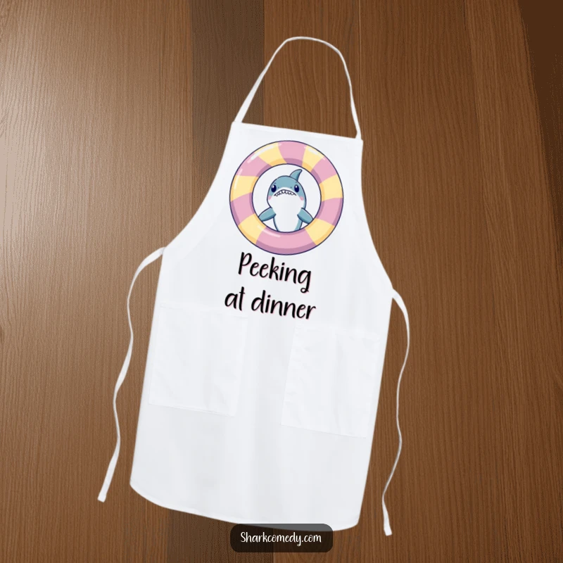 Funny shark peeking from behind an inflatable ring, printed on a kitchen apron, making cooking more amusing.