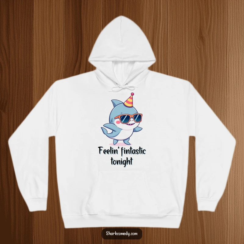 Funny shark wearing oversized sunglasses and a tiny party hat, dancing energetically on a warm, cozy hoodie.