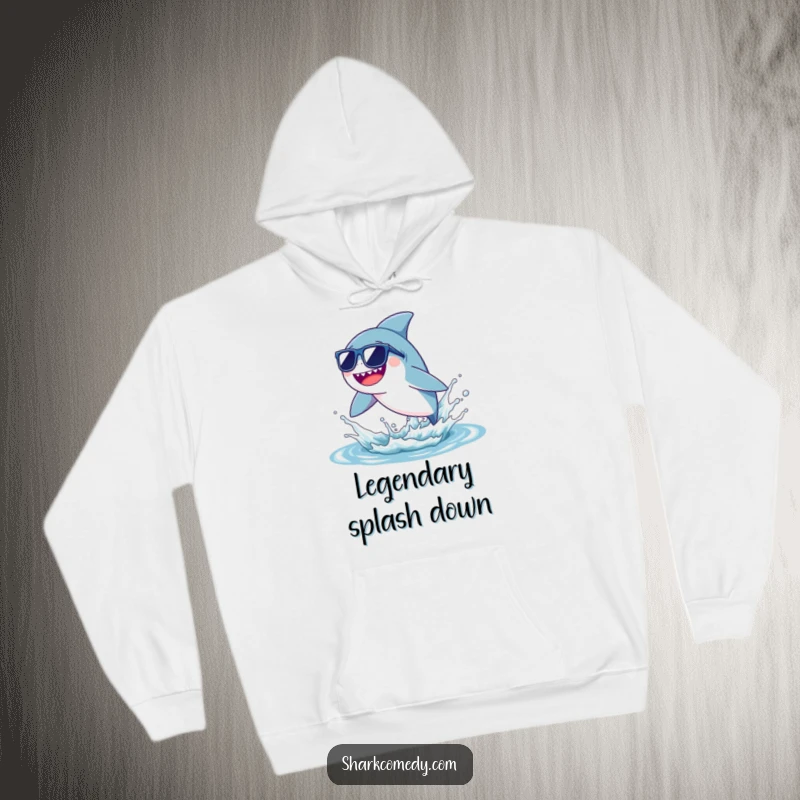 Comfortable hoodie featuring a funny tiny shark wearing sunglasses, leaping joyfully from a water splash, ideal for cool humor.
