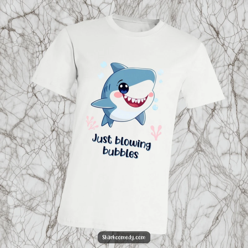 Funny smiling shark character, blowing bubbles underwater with wide, happy eyes, printed on a comfortable graphic tee.